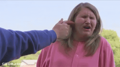 A Woman In A Pink Shirt Is Being Punched In The Face By A Man . GIF