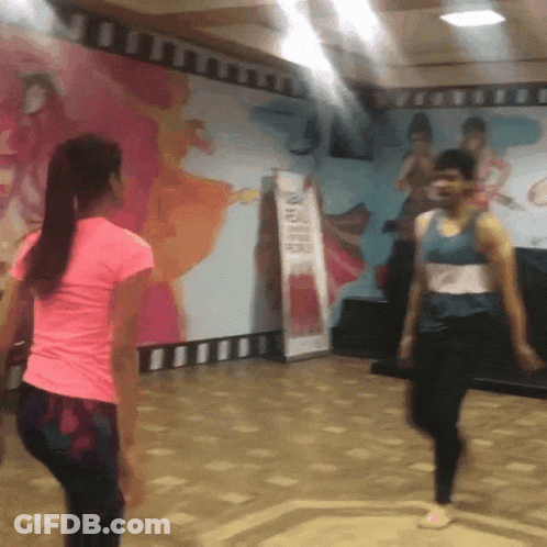 A Woman In A Pink Shirt Is Dancing In Front Of A Sign That Says ' A ' On It GIF