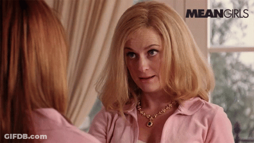 A Woman In A Pink Shirt Is Looking At Another Woman In Front Of A Window With Meangirls Written On The Bottom GIF