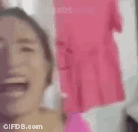 A Woman In A Pink Shirt Is Looking At The Camera . GIF