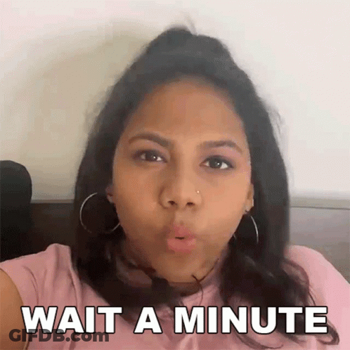 A Woman In A Pink Shirt Is Making A Funny Face And Says Wait A Minute GIF