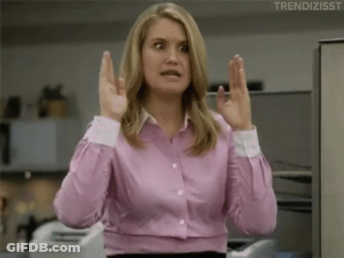 A Woman In A Pink Shirt Is Making A Funny Face With Her Hands Up . GIF