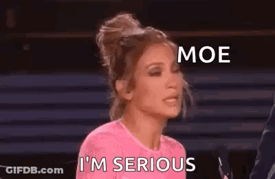 A Woman In A Pink Shirt Is Sitting In Front Of A Microphone And Making A Funny Face . GIF