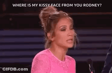 A Woman In A Pink Shirt Is Sitting In Front Of A Microphone . GIF
