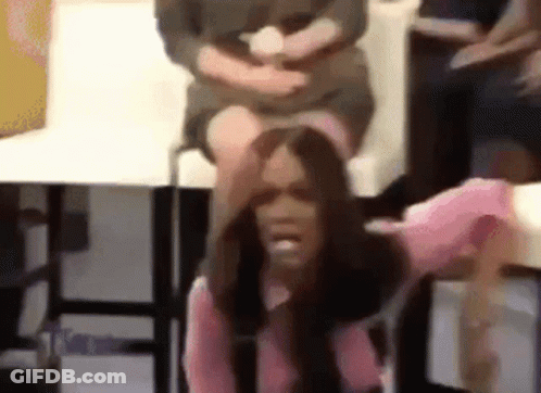 A Woman In A Pink Shirt Is Sitting On A Chair With Her Hand On Her Head . GIF