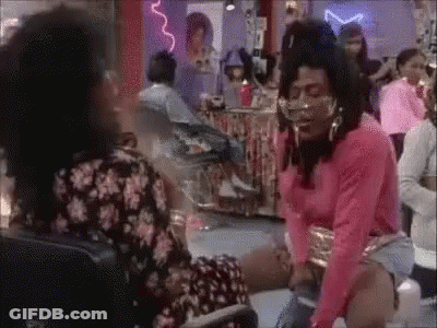 A Woman In A Pink Shirt Is Sitting On The Floor In A Room With A Group Of People . GIF