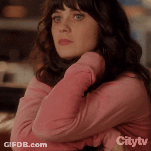A Woman In A Pink Shirt Is Sitting With Her Arms Crossed In Front Of A Citytv Sign GIF