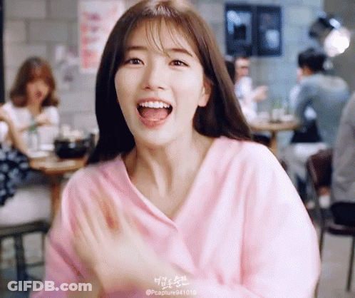 A Woman In A Pink Shirt Is Smiling With Her Tongue Out GIF