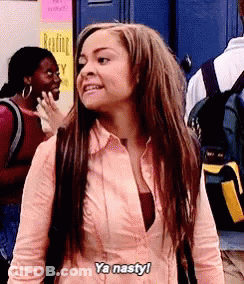 A Woman In A Pink Shirt Is Standing In Front Of A Blue Door . GIF