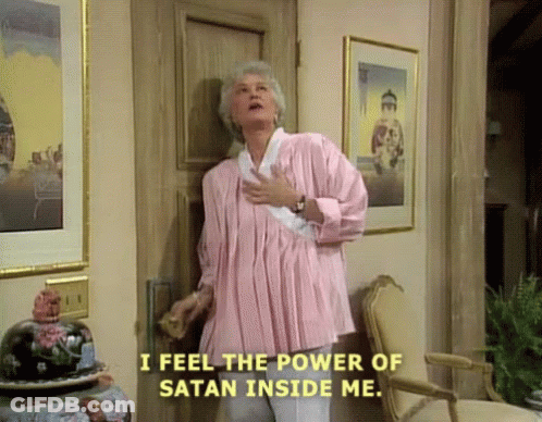 A Woman In A Pink Shirt Is Standing In Front Of A Door Saying I Feel The Power Of Satan Inside Me . GIF