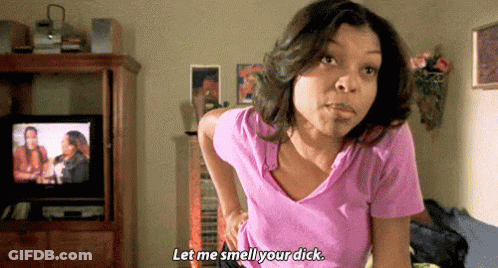 A Woman In A Pink Shirt Is Standing In Front Of A Television And Saying " Let Me Smell Your Dick " . GIF