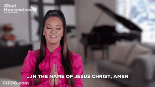 A Woman In A Pink Shirt Prays In Front Of A Piano GIF