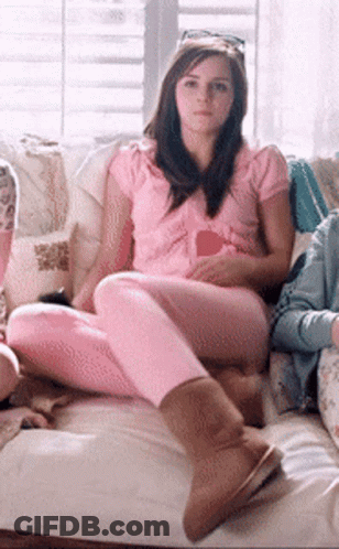 A Woman In A Pink Shirt Sits On A Couch GIF