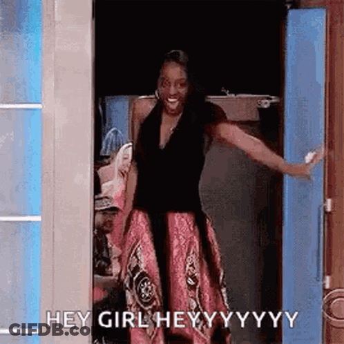 A Woman In A Pink Skirt Is Standing In A Doorway With Her Arms Outstretched . GIF