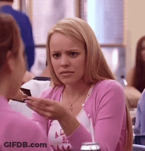 A Woman In A Pink Sweater Is Holding A Piece Of Cake In Her Hand And Talking To Another Woman . GIF