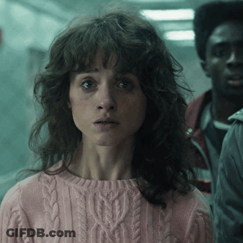 A Woman In A Pink Sweater Is Looking At The Camera GIF