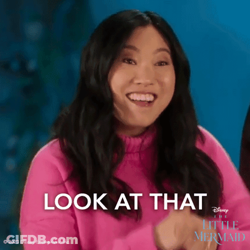 A Woman In A Pink Sweater Is Smiling With The Words Look At That Behind Her GIF