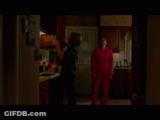 A Woman In A Pink Sweater Is Standing In A Kitchen GIF