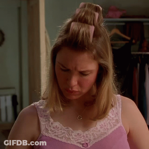 A Woman In A Pink Tank Top And White Lace Trim Looks Down GIF