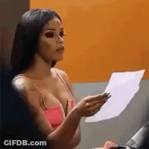 A Woman In A Pink Tank Top Is Holding A Piece Of Paper In Her Hand . GIF