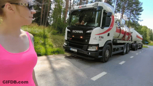 A Woman In A Pink Tank Top Is Standing In Front Of A Scania Truck GIF