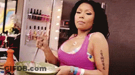 A Woman In A Pink Tank Top Is Stirring Something In A Bowl . GIF
