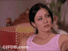 A Woman In A Pink Tank Top Sits On A Couch GIF