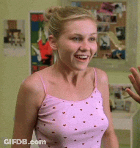 A Woman In A Pink Tank Top With Hearts On It Is Smiling GIF