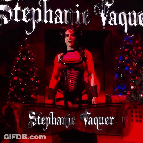 A Woman In A Pink Top And Black Corset Is Standing In Front Of A Red Background With The Name Stephanie Vaquer On It . GIF