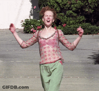 A Woman In A Pink Top And Green Pants Is Screaming With Her Arms In The Air GIF