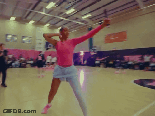 A Woman In A Pink Top And White Shorts Is Holding A Sword GIF