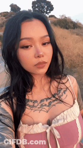 A Woman In A Pink Top Has A Tattoo On Her Chest That Says " I 'M A Girl " GIF