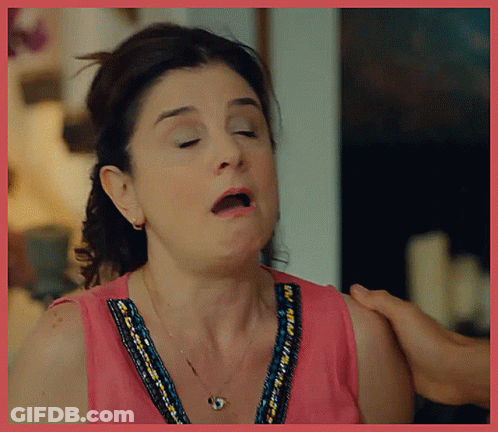 A Woman In A Pink Top Is Making A Funny Face With Her Mouth Open GIF