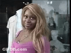 A Woman In A Pink Top Is Standing In Front Of A Mannequin In A Store . GIF