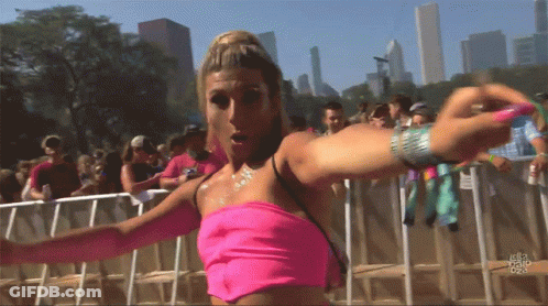 A Woman In A Pink Top Stands In Front Of A Crowd At A Festival GIF