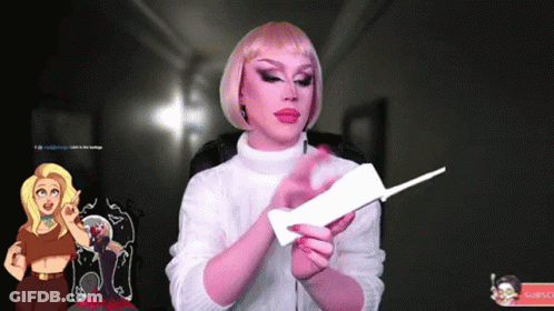 A Woman In A Pink Wig Is Holding A Piece Of Paper GIF