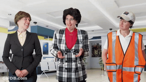 A Woman In A Plaid Jacket Stands Next To Two Other Women GIF