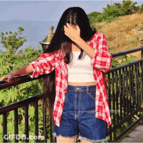 A Woman In A Plaid Shirt And Shorts Covering Her Face GIF
