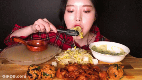 A Woman In A Plaid Shirt Is Eating A Meal With Tongs GIF