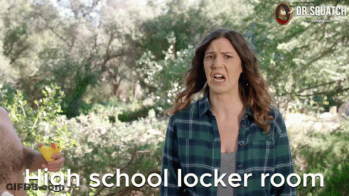 A Woman In A Plaid Shirt Is Holding A Yellow Rubber Duck In Front Of Trees And The Words High School Locker Room GIF