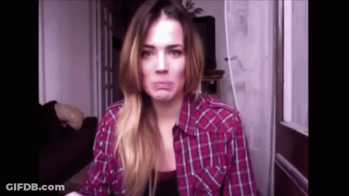 A Woman In A Plaid Shirt Is Making A Face . GIF