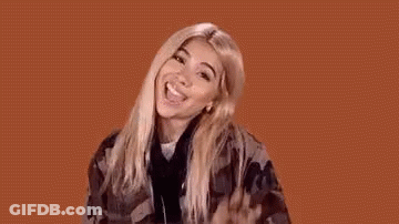 A Woman In A Plaid Shirt Is Making A Funny Face And Waving Her Hand In The Air . GIF