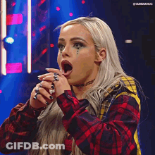 A Woman In A Plaid Shirt Is Making A Funny Face With Her Mouth Open . GIF