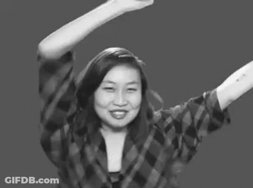 A Woman In A Plaid Shirt Is Raising Her Arms In The Air . GIF