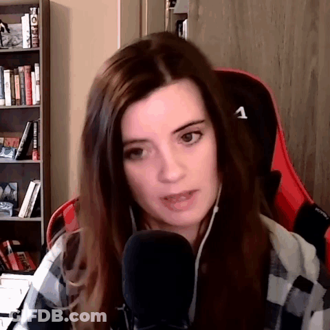 A Woman In A Plaid Shirt Is Sitting In A Red Chair With A Microphone . GIF
