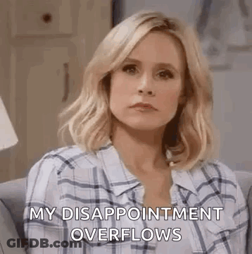 A Woman In A Plaid Shirt Is Sitting On A Couch And Making A Sad Face . GIF