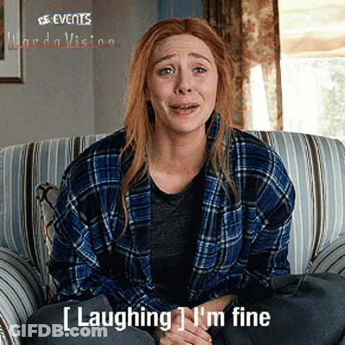 A Woman In A Plaid Shirt Is Sitting On A Couch With The Words Laughing I 'M Fine Below Her GIF