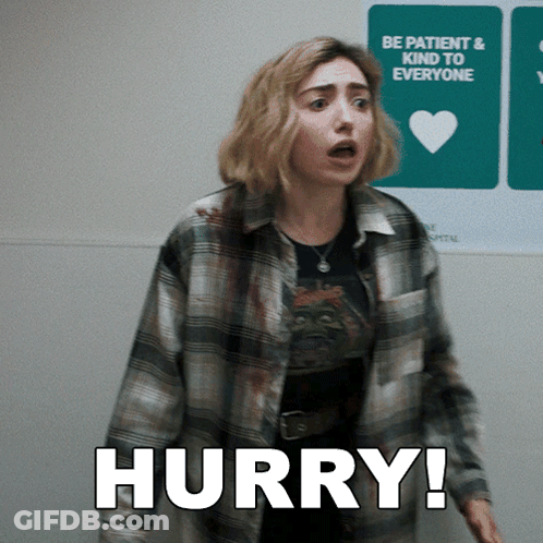 A Woman In A Plaid Shirt Is Standing In Front Of A Sign That Says Hurry GIF