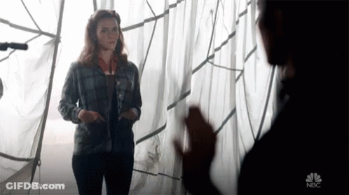 A Woman In A Plaid Shirt Is Standing Next To A Man In A Black Shirt With Nbc Written On The Bottom Right GIF