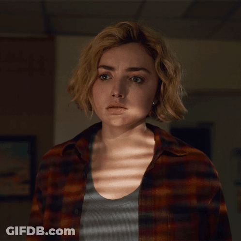 A Woman In A Plaid Shirt Looks At The Camera With A Serious Look On Her Face GIF